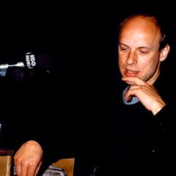 Brian Eno seated onstage during his appearance at Speaking of Music at the Exploratorium, 1988