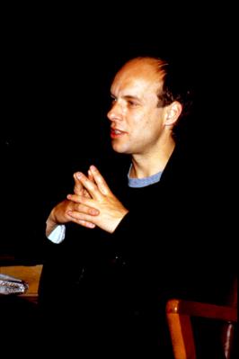 Side view of Brian Eno seated onstage during Speaking of Music at the Exploratorium, 1988
