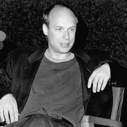 Brian Eno, seated onstage during Speaking of Music at the Exploratorium, 1988