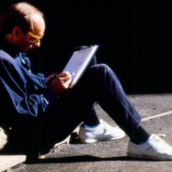 Brian Eno writing, seated on the ground outside the Exploratorium, 1988