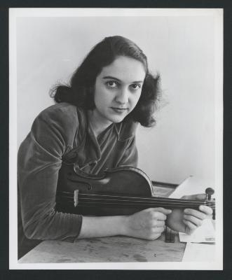 Portrait of violinist Anahid Ajemian, with arms and violin resting on a table (ca. 1940s)