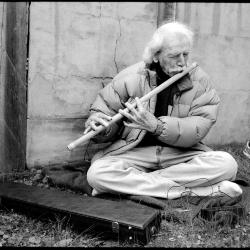 G. S. Sachdev, seated on the ground outdoors playing the bansuri flute, Woodside, CA (2013)