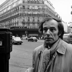 Bernard Heidsieck, head and shoulders portrait with "Les Monde des Jouets" in background, Paris, 1973