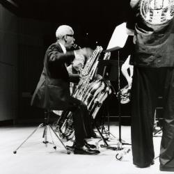 Roscoe Mitchell, seated, playing bass saxophone during a rehearsal for OM 19 (2014)