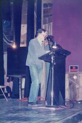 John Cage, standing onstage at a podium, ca. 1987