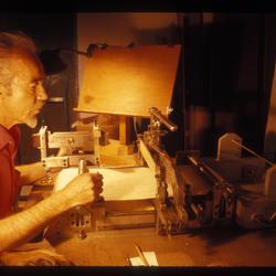 A portrait of Conlon Nancarrow seated at his piano roll punching machine, 1969