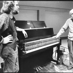 Trimpin, facing right, and Conlon Nancarrow, facing camera,standing, flanking a modified piano, (1993)