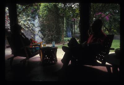 A dark image of Carol Law and Conlon Nancarrow seated on Nancarrow's porch outside, 1969
