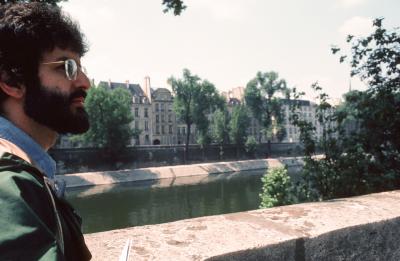 Charles Amirkhanian, facing right, by a bank of the river Seine, Paris, France, 1976