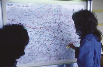 Two people looking at a map of the subway lines in Paris, France, 1976