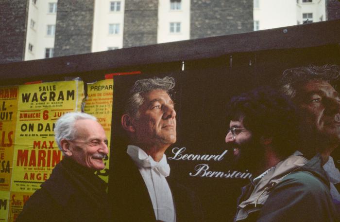 Ivan Wyschnegradsky and Charles Amirkhanian standing in front of a billboard image of Leonard Bernstein, Paris (1976)