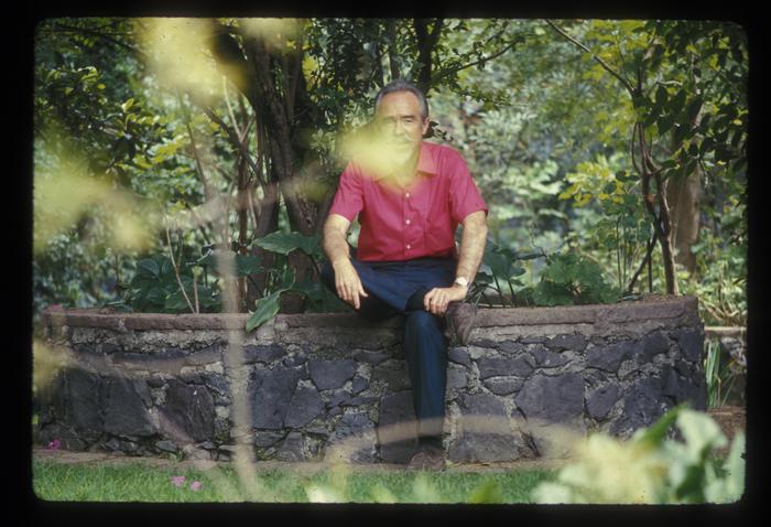 Portrait of Conlon Nancarrow, seated in his garden on a stone bench, 1969