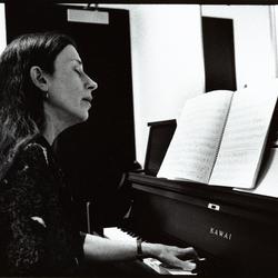 Meredith Monk facing forward, head and shoulders portrait, playing the piano, 1993 (cropped image)