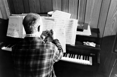 Leo Ornstein, seated at a piano, marking a score, Brownsville TX, 1981