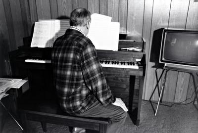 Leo Ornstein, seated at his piano with his back to the camera, Brownsville TX, 1981