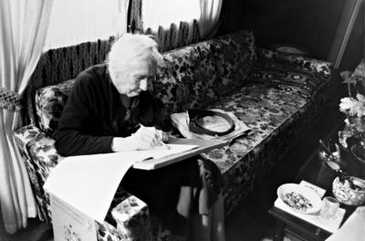 Pauline Ornstein seated, examining a document, Brownsville TX, 1981